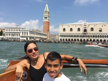Smiling mother and son traveling in boat over grand canal against san giorgio maggiore