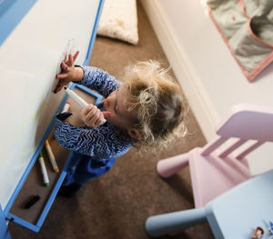 High angle view of girl drawing on canvas at home