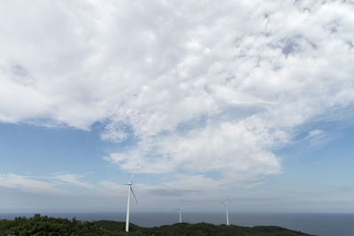 Low angle view of wind turbines against sky