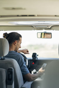 Young man text messaging through smart phone sitting in van