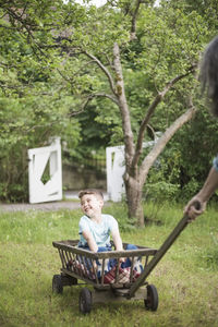Grandmother pulling cart with smiling boy at back yard