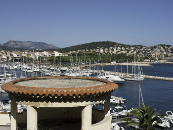 Sailboats in sea by mountains against clear blue sky