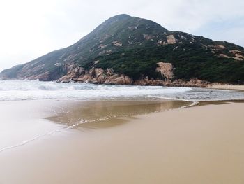 Scenic view of beach and mountains against sky