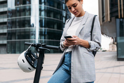Woman using an app to unlock the electric push scooter. businesswoman holding smartphone 
