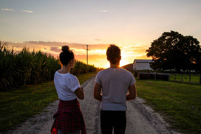 Rear view of friends standing on grassy field