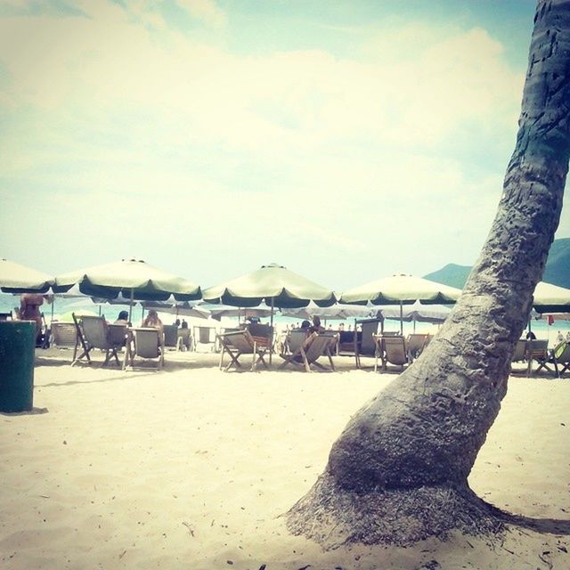 beach, sand, shore, sky, sea, water, vacations, beach umbrella, tranquil scene, relaxation, tranquility, nature, scenics, incidental people, cloud - sky, cloud, day, parasol, sunlight, horizon over water