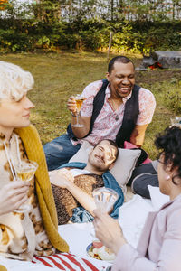 Happy gay man enjoying drinks with lgbtq friends in back yard