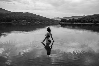 Woman standing in lake against sky