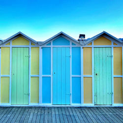 Closed wooden door of building against clear blue sky