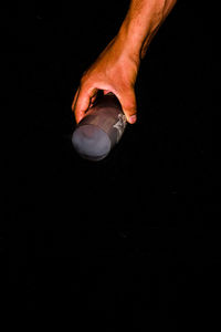 Close-up of hand holding cigarette against black background