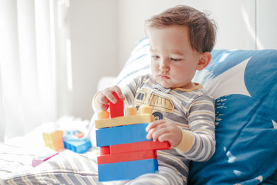 Boy with toy on bed at home