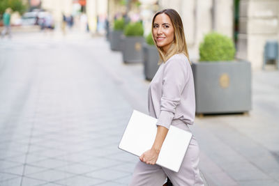 Portrait of young woman standing in city