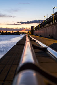 Surface level of pipes by sea against sky during sunset