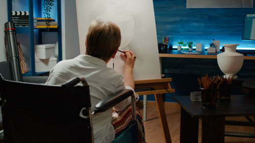 Rear view of woman sitting on chair at home