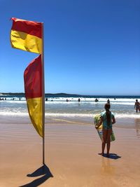 Flag on beach against clear sky