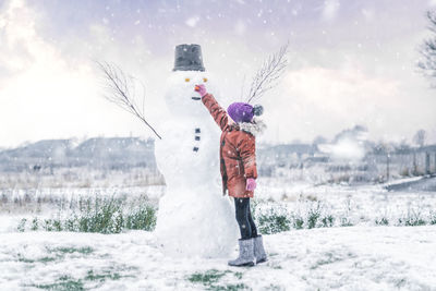 Rear view of woman standing on snow covered landscape