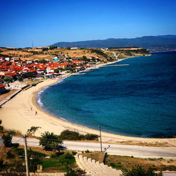 High angle view of townscape by sea against blue sky