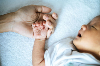 Close-up of baby sleeping on bed with mother at home