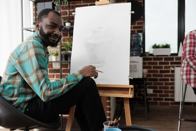 Portrait of young man using laptop while sitting on table