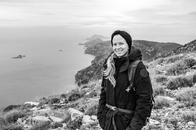 Portrait of young woman standing against mountain