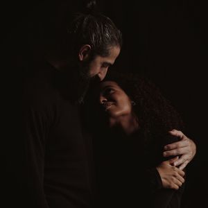 Couple embracing against black background
