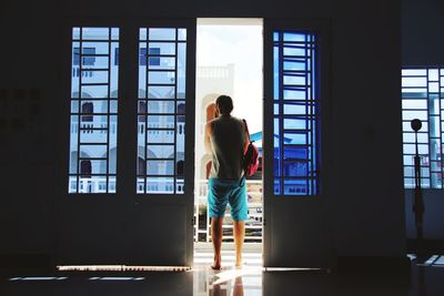 Rear view of man standing by window in building