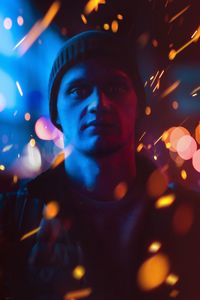 Portrait of man against illuminated lights at night