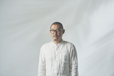 Man standing with eyes closed against white background