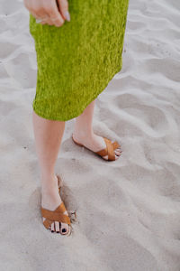 Low section of woman standing on sand