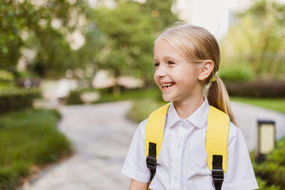 Back to school. little girl with yellow backpack from elementary school outdoor