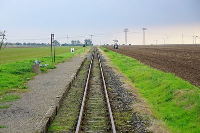 Railroad track amidst field against clear sky