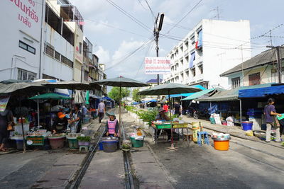 People in market against sky in city