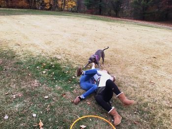 High angle view of playful couple with dog on field