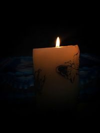 Close-up of lit candle against black background