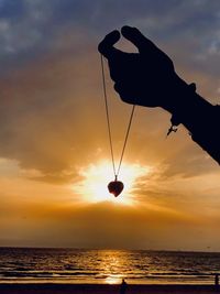 Silhouette person by sea against sky during sunset