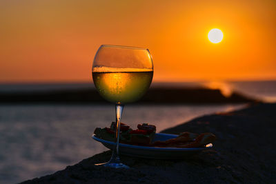Close-up of wineglass against orange sunset sky
