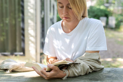 Mid adult woman reading book outdoors