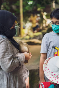 Pigeon eating from the hand of a young hijab girl.