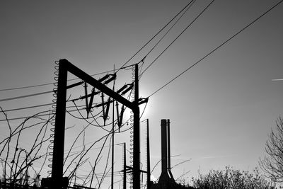 Low angle view of silhouette electricity pylon against sky during sunset