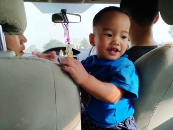 Portrait of cute boy sitting on car