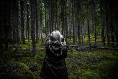 Rear view of woman photographing with camera while standing at forest