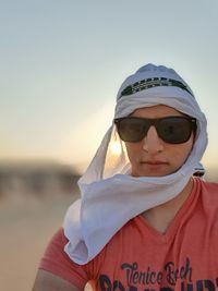 Portrait of man wearing sunglasses and headscarf against sky during sunset
