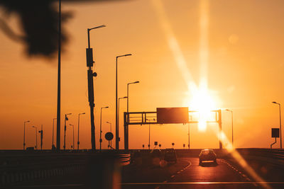 Cars on street against orange sky during sunset