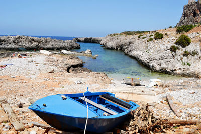 Blue boat moored on shore against sky