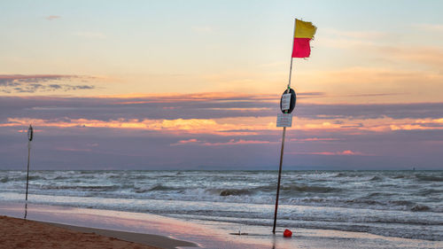 Lifeguard hut on beach against sky during sunset