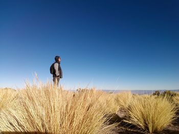 Side view of man standing on field against clear sky