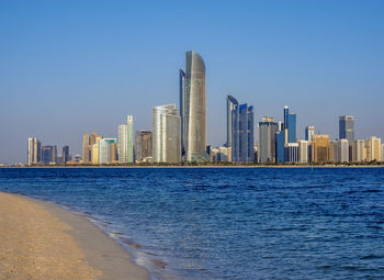 Sea by buildings against clear sky