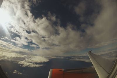 Cropped image of airplane wing over clouds