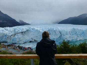 Rear view of woman looking at snowcapped mountain against sky