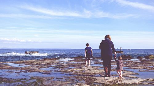 Rear view of woman with daughter and son at beach